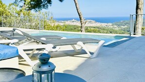 A poolside area with lounge chairs, a table, and a lantern. - Cardina CostaBravaSi - Pool, A/C, barbecue, views (Sant Feliu de Guíxols)