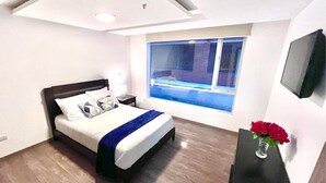 Un dormitorio moderno con una cama grande, una mesita de noche, un escritorio y una ventana con vistas al exterior.