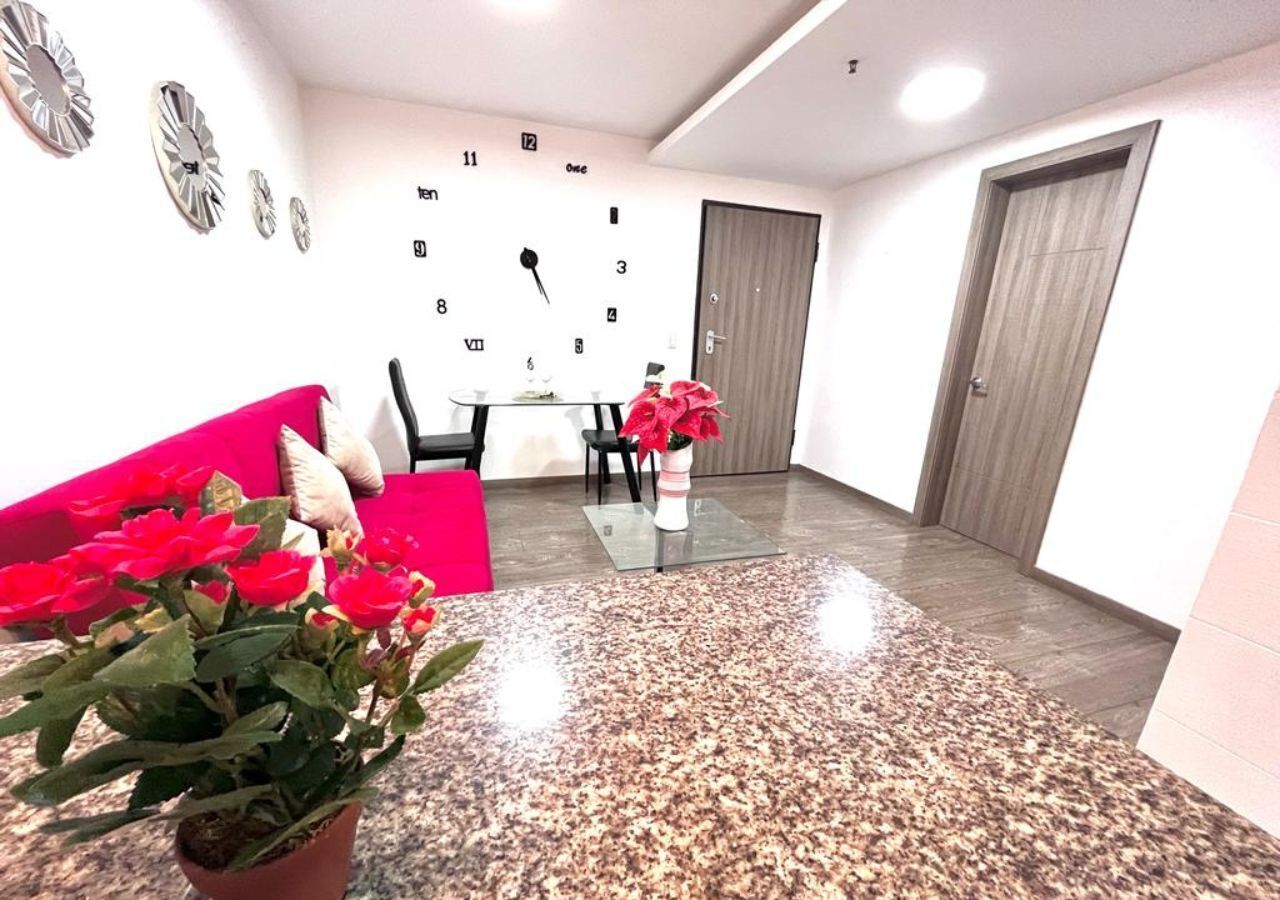A modern interior with a granite countertop, a dining table with chairs, a clock on the wall, and a door.