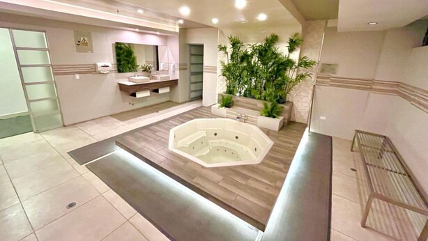 Un baño moderno con una bañera grande, un tocador de madera y un jardín vertical con plantas.