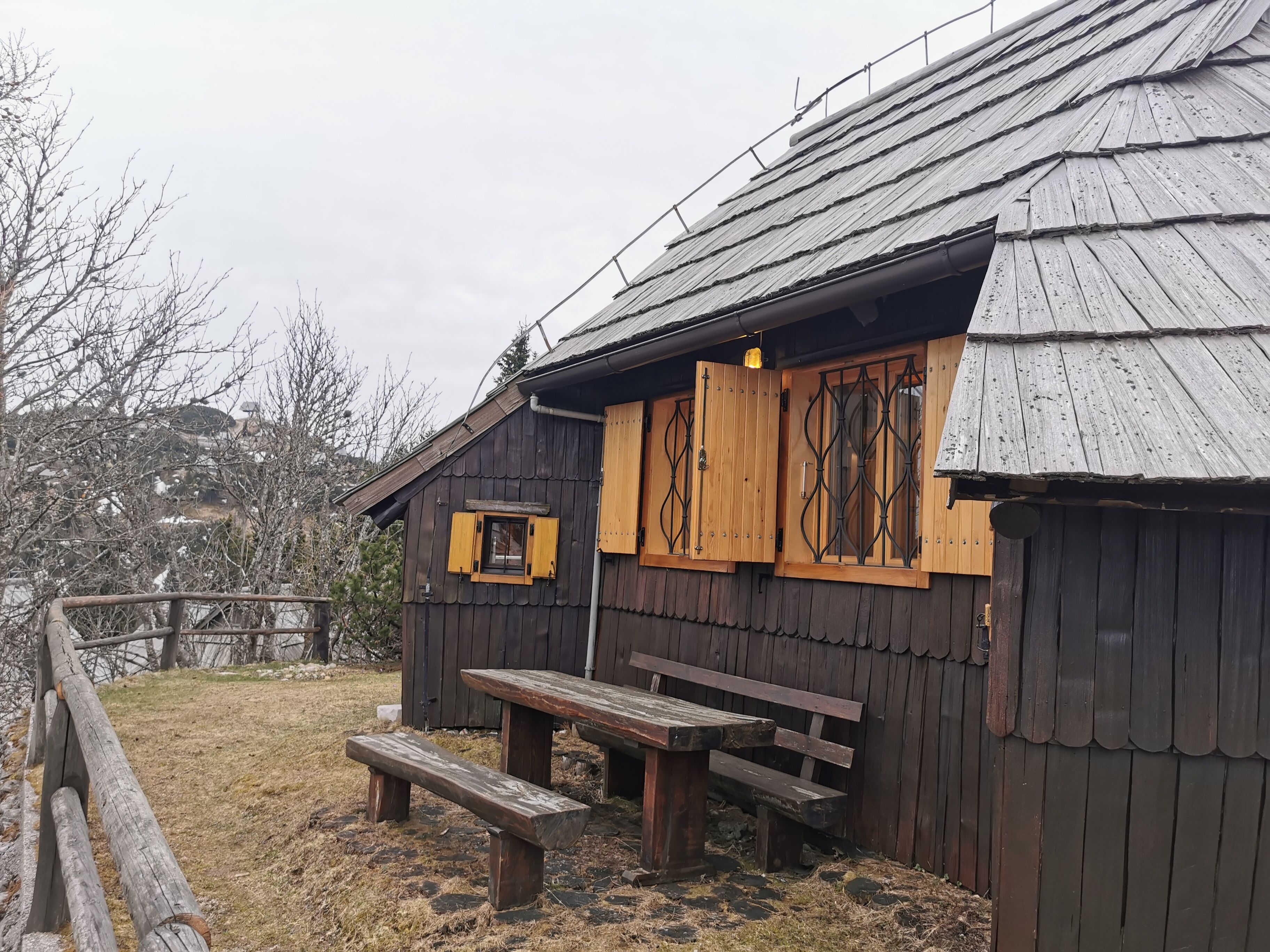 A rustic wooden cabin with a bench and a table outside.