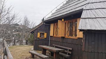 A rustic wooden cabin with a bench and a table outside.
