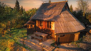 A rustic wooden cabin with a sloped roof, a porch, and a small table and bench.