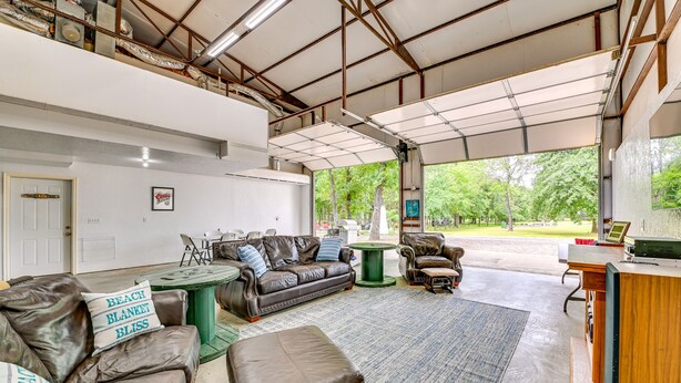 A spacious living area with a high ceiling, a large window, and a view of the outdoors. - Spacious Lake Texoma Vacation Rental w/ Game Room! (Kingston)
