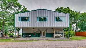 A two-story metal building with a covered porch and a small outdoor seating area. - Spacious Lake Texoma Vacation Rental w/ Game Room! (Kingston)