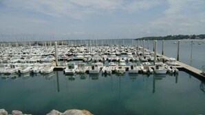 A marina with numerous boats docked in calm water, surrounded by a rocky shoreline.