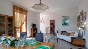 Un comedor con una mesa de madera dispuesta para una comida, un sofá y una lámpara de pie.
