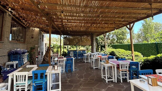 An outdoor patio with stone flooring and tables and chairs. - Assos Gül pansiyon (Ayvacik)