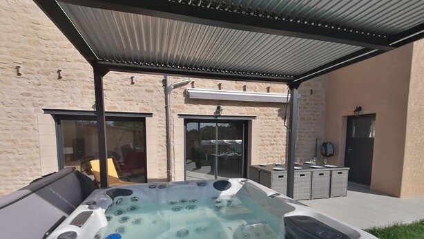 Un jacuzzi en un espacio exterior techado, con un edificio de piedra al fondo.