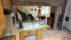 Une cuisine avec un îlot central en bois, un lave-vaisselle encastré et un mur en briques.