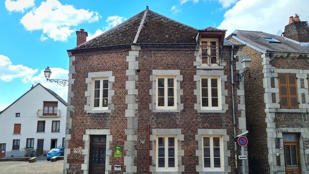 Un bâtiment historique à la façade en briques, doté de nombreuses fenêtres et d’une porte de style traditionnel.