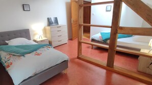 Une chambre à coucher avec un lit, une commode, une table de chevet, une échelle en bois et un lit superposé.