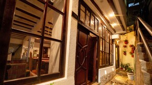 A building with a large wooden door, a staircase, and a small outdoor area with potted plants. - Vilas Insight Hotel Machupicchu (Machu Picchu)