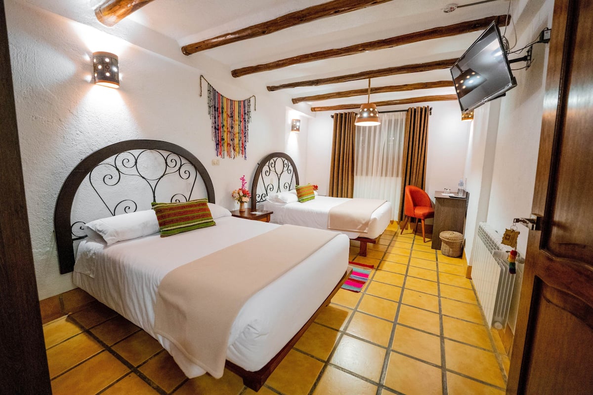 A hotel room with two beds, a TV, a desk, and a chair.