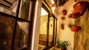 A narrow corridor with a window on the left and a wall adorned with potted plants. - Vilas Insight Hotel Machupicchu (Machu Picchu)