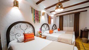 A hotel room with three beds, each with a unique headboard design, white bedding, and colorful pillows. There are wall-mounted lights and a window with curtains. - Vilas Insight Hotel Machupicchu (Machu Picchu)
