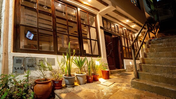 A building with multiple windows, a staircase, and several potted plants on the ground. - Vilas Insight Hotel Machupicchu (Machu Picchu)