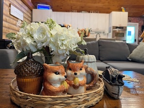 Een rieten mand met keramische dierenbeeldjes en een vaas witte bloemen op een houten tafel.