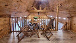 Ein Holzinnenraum mit hoher Decke, einem Holztisch mit zwei Stühlen und einem kleinen Blumentopf.