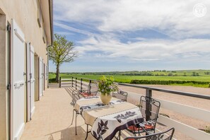 Una terraza con mesa lista para comer, con vistas a un paisaje verde.