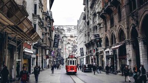 A tram moving through a city street lined with historic buildings and shops. - Atik Suite Taksim  (Istanbul)