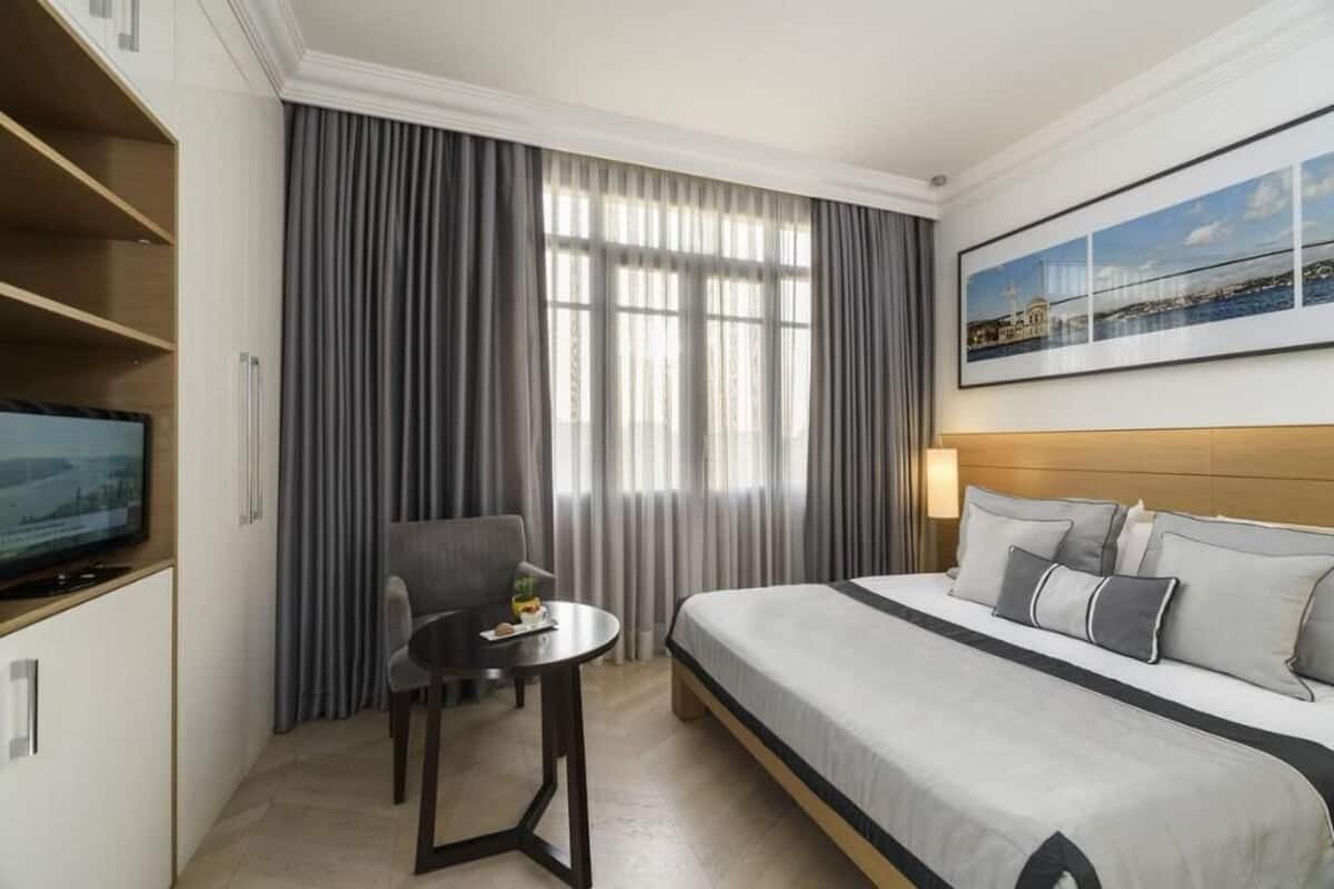 A hotel room with a bed, a TV, a desk, and a chair.
