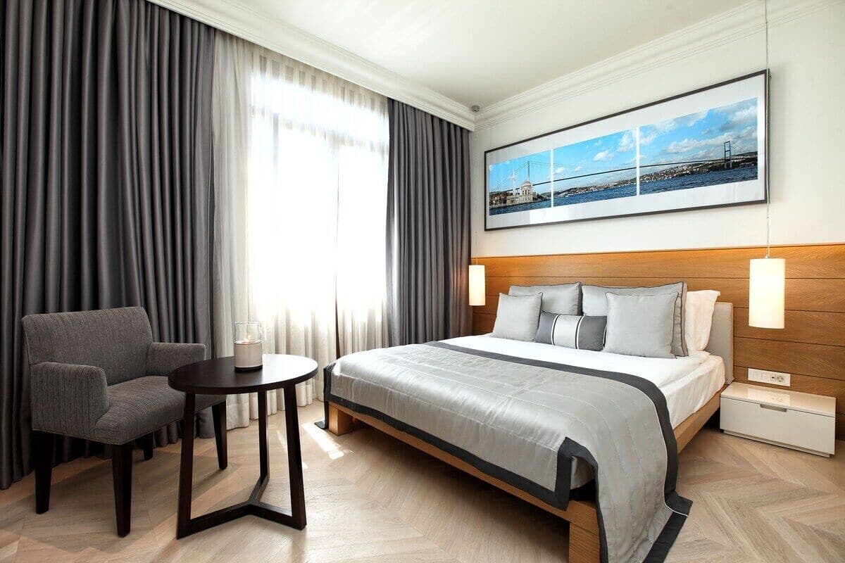 A hotel room with a bed, a chair, a small table, and a nightstand.