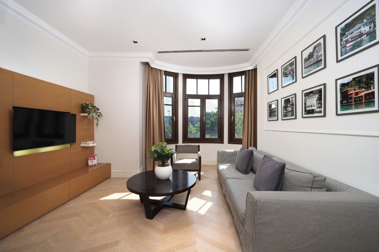A modern living room with a flat-screen TV, a round coffee table, a sofa, and a dining table.