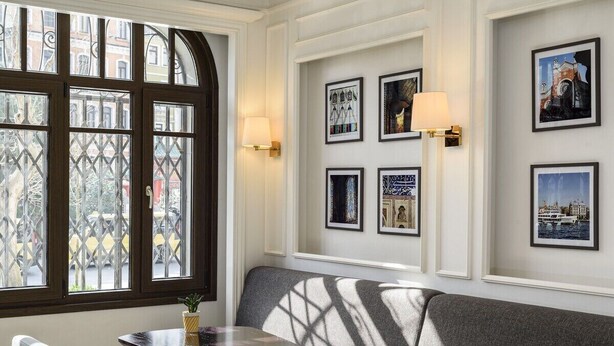 A room with a large window, a sofa, a small table, and wall-mounted lamps. - Atik Suite Taksim  (Istanbul)
