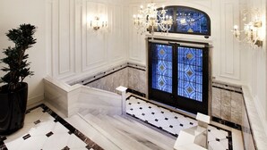 A grand hallway with a marble floor, a large potted plant, a decorative chandelier, and a stained glass window. - Atik Suite Taksim  (Istanbul)