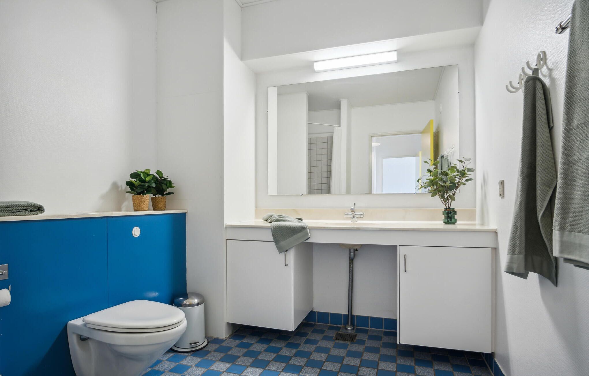 Un baño con inodoro, lavamanos, espejo y toallero.