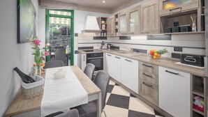 A compact kitchen with a dining area, featuring a checkered floor, wooden cabinets, and a dining table with chairs. - Nice apartment in Buzet (Buzet)