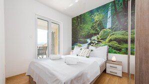 A bedroom with a bed, a nightstand, a mirror, and a large wall mural of a forest scene. - Stunning apartment in Bibinje with WiFi (Bibinje)