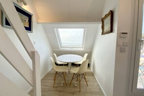 A small room with a skylight, a round table with chairs, and a door leading outside. - Appartement Avec Terrasse , Surplombant la Baie de Somme (Le Crotoy)