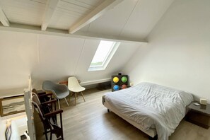 A bedroom with a bed, a desk, a chair, a window, and a radiator. - Appartement Avec Terrasse , Surplombant la Baie de Somme (Le Crotoy)