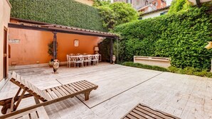 Um pátio com mesa e cadeiras, um banco de madeira e uma parede coberta de vegetação.