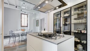 Uma cozinha moderna com ilha central, armários de vidro e área de refeições com cadeiras transparentes.