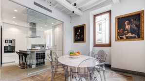 Uma cozinha moderna com área de jantar, cadeiras transparentes e obras de arte nas paredes.