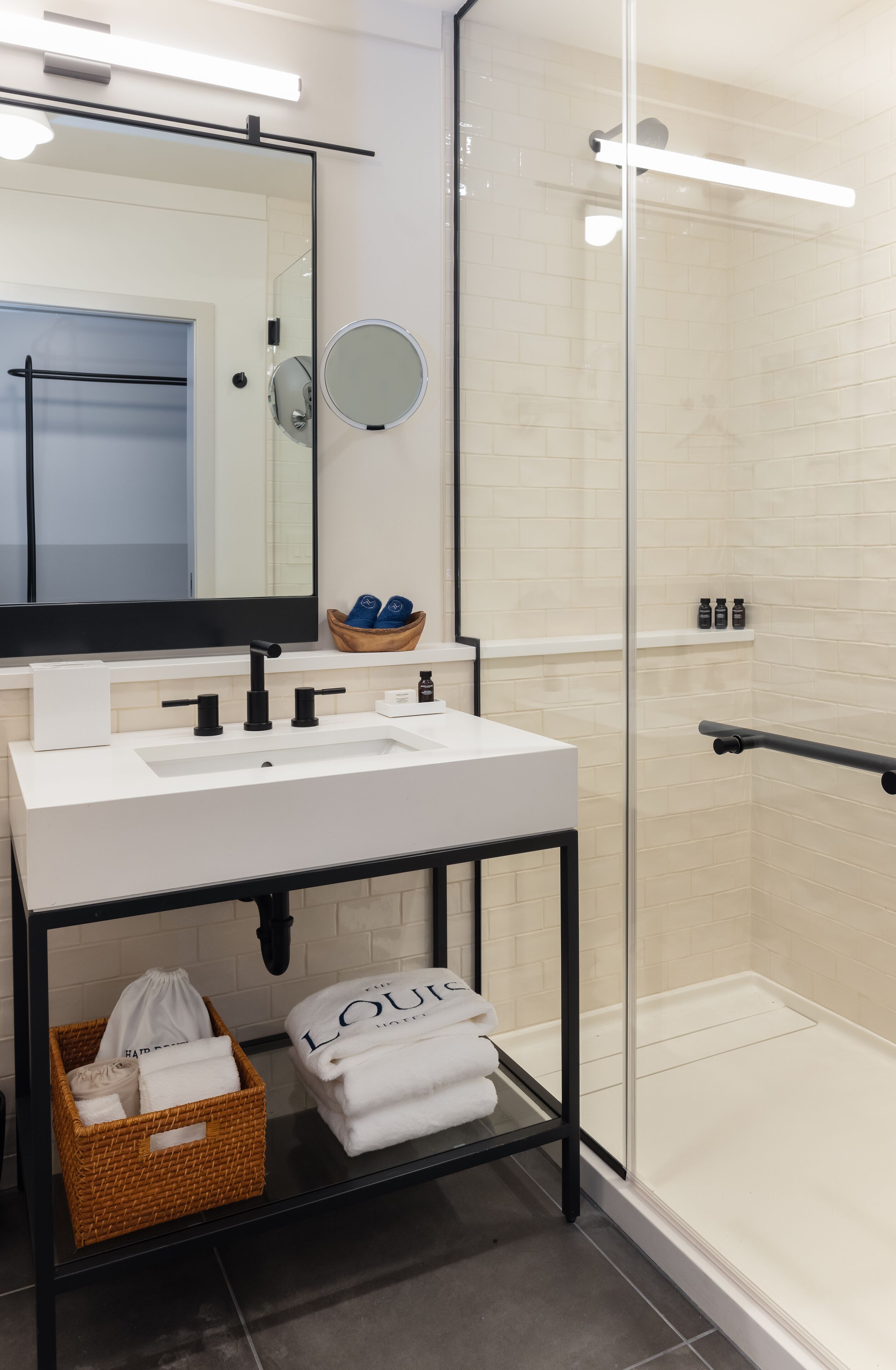 A modern bathroom with a white sink, black faucet, and a glass shower enclosure.