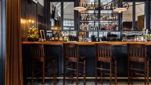 Un espace bar avec des chaises en bois, un comptoir et des étagères remplies de bouteilles.