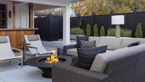 Un espace extérieur aménagé en terrasse, avec des meubles en osier, un foyer et un coin salon abrité.
