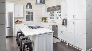 Une cuisine moderne avec des meubles blancs, un îlot central et des tabourets de bar.