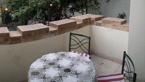 A small outdoor seating area with a table and chairs, a low stone wall, and a tree providing shade. - alojarseenmendoza  (Mendoza)