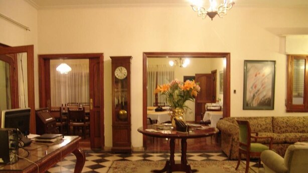A living room with a checkered floor, a round table with a vase of flowers, a sofa, and a clock on the wall. - alojarseenmendoza  (Mendoza)