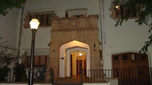 A building with a stone archway entrance, a metal lamp post, and a gated driveway. - alojarseenmendoza  (Mendoza)
