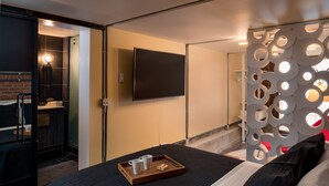 A modern hotel room with a bed, a tray with cups and a box, a TV on the wall, and a decorative partition. - Queen Anne Design Studio, 7days max. (Seattle)