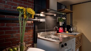 A modern kitchen with a stainless steel stove, a sink, and a brick wall. There are flowers in a vase on the counter. - Queen Anne Design Studio, 7days max. (Seattle)