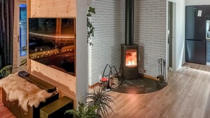 A cozy room with a wood-burning stove, a large window, and a modern kitchen area.