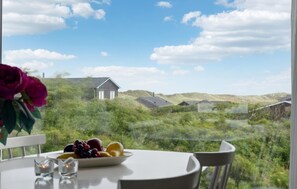 Una mesa de comedor con un frutero y velas, con vistas a un paisaje de casas y colinas.