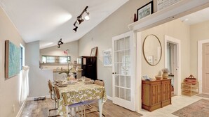 A dining area with a table set for four, a wooden cabinet, and a large mirror. - Cozy High Springs Retreat Near Blue Springs, Renovated Pet-Friendly Backyard! (High Springs)